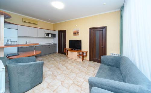 a living room with two blue chairs and a kitchen at Sovinyon Resort in Odesa