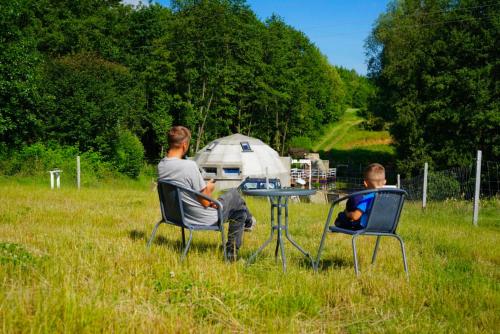 two men sitting at a table in a field at Bunkier House in Niedźwiada