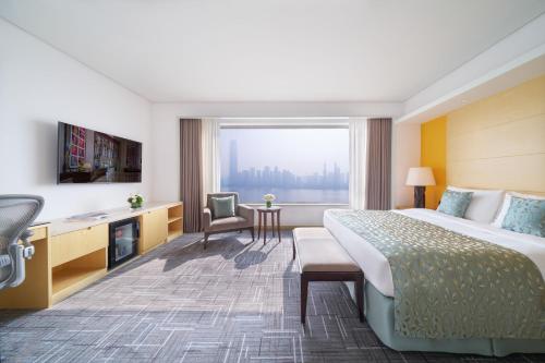 a hotel room with a bed and a large window at Marco Polo Wuhan in Wuhan