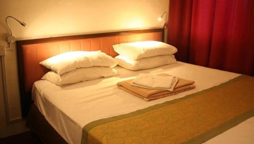 a bed with white pillows and towels on it at Red Inn Court in George Town
