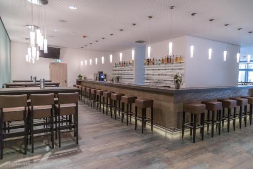 a bar in a restaurant with brown stools at B&F Hotel am Neumarkt in Bad Hersfeld
