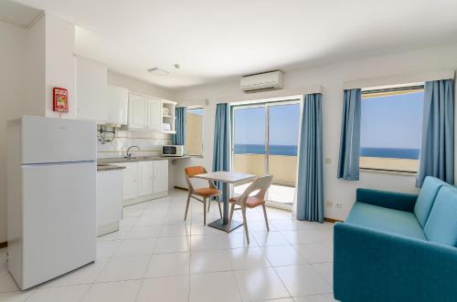 a kitchen and living room with a table and chairs at TURIM Algarve Mor Apartamentos Turísticos in Portimão