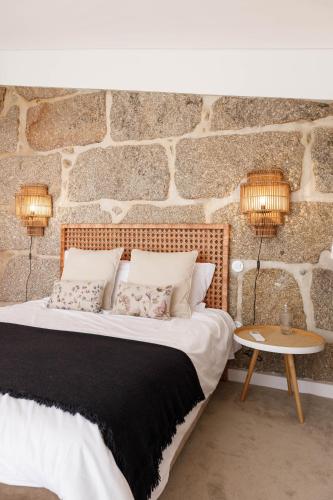 a bedroom with a bed and a stone wall at Casa da Bisa Rita in Aldeia Formosa