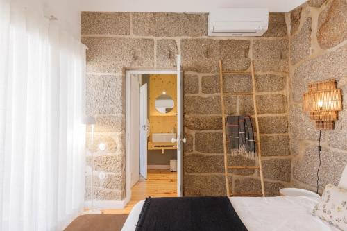 a bedroom with a stone wall with a bed at Casa da Bisa Rita in Aldeia Formosa