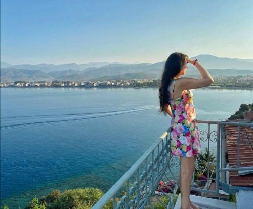 a woman standing on a balcony looking at the water at Ece Hotel Sovalye Island in Fethiye