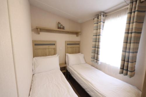 two beds in a small room with a window at Mercury Yacht Harbour and Holiday Park in Bursledon