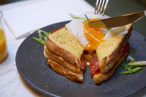 a sandwich with egg and bacon on a plate with a fork at The Store in Oxford
