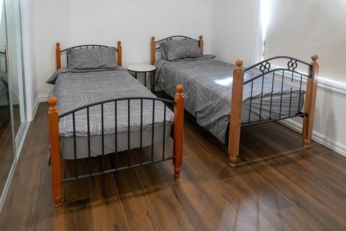 two twin beds in a room with wooden floors at Hodgson in Tarneit
