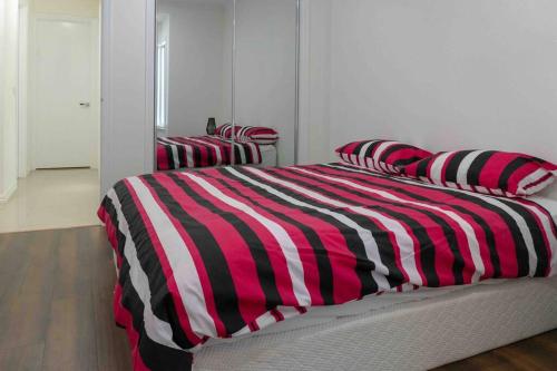 a bed with a red and black striped blanket at Hodgson in Tarneit