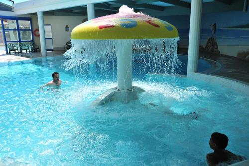 deux personnes dans une piscine avec une fontaine dans une piscine dans l'établissement Mobile Home avec piscine dans Camping calme Proche plage, à Saint-Hilaire-de-Riez