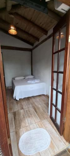 a bedroom with a white bed and a large window at Pousada Prumirim Surf Suítes in Ubatuba