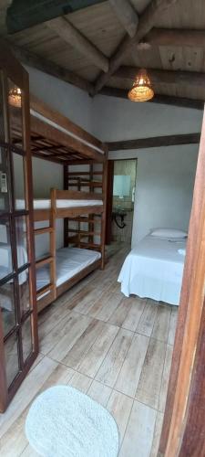 a bedroom with two bunk beds and a wooden floor at Pousada Prumirim Surf Suítes in Ubatuba