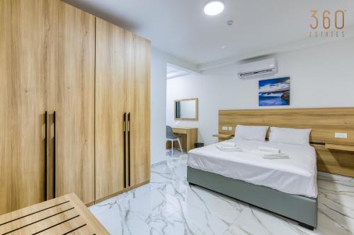 a bedroom with a large bed and a wooden cabinet at The St Pauls Bay Escape Suites by 360 Estates in St Paul's Bay
