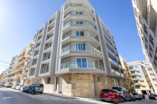 a tall apartment building with cars parked in front of it at The St Pauls Bay Escape Suites by 360 Estates in St Paul's Bay