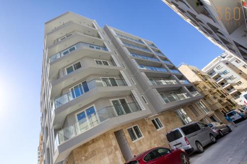 a tall building with cars parked in front of it at The St Pauls Bay Escape Suites by 360 Estates in St Paul's Bay