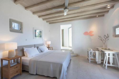 een witte slaapkamer met een bed en een tafel bij Villa Calithenean in Mykonos-stad