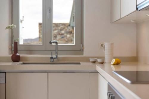 een witte keuken met een wastafel en een raam bij Villa Calithenean in Mykonos-stad