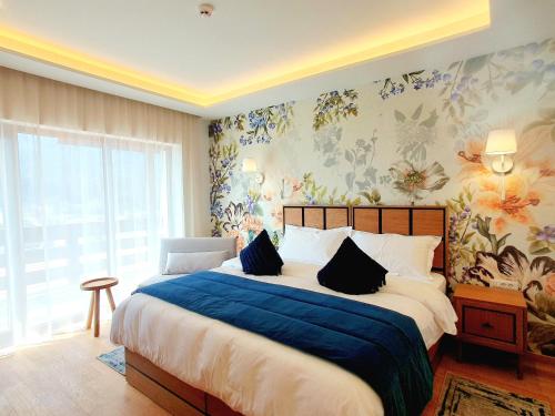 Schlafzimmer mit einem Bett mit blauer Bettwäsche und Blumentapete in der Unterkunft Pensiunea Leonida - RESORT LEONIDA in Poiana Ţapului