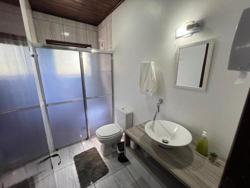 a bathroom with a shower and a toilet and a sink at Pousada Recanto da Palmeira in Guaíba