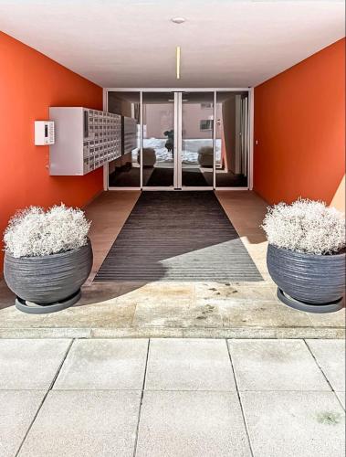 two large pots on the floor in a room with an orange wall at St Moritz Suite in St. Moritz