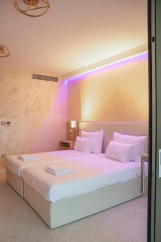 a bedroom with a large white bed with purple lights at Orlovo gnezdo in Ljubovija