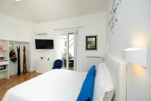 a white bedroom with a bed and a tv at Villa Torù in Castellabate