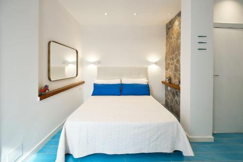 a bedroom with a white bed with blue pillows at Villa Torù in Castellabate