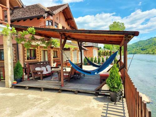 a wooden deck with a hammock and a house at Vila Vitezov Mir - Drina in Vrhpolje