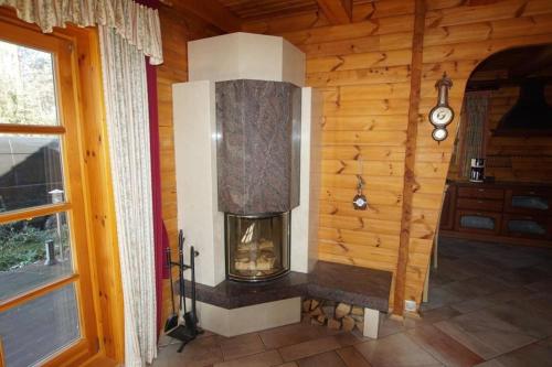 a fireplace in a log cabin with a window at Schönes Ferienhaus in Schmiedeberger Weinberge mit Terrasse und Grill in Bad Schmiedeberg