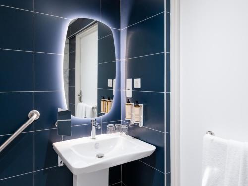 a blue bathroom with a sink and a mirror at Mercure Nancy Centre Place Stanislas in Nancy