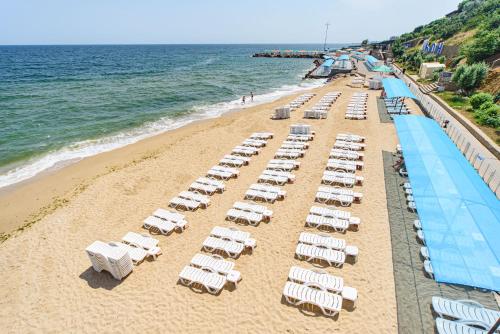 a beach with a bunch of lounge chairs and the ocean at Sovinyon Resort in Odesa