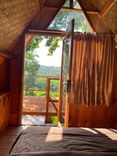 a bedroom with a large window in a cabin at The Alam Bungalow & Restaurant in Tetebatu
