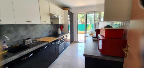 - une cuisine équipée de comptoirs noirs et d'un réfrigérateur rouge dans l'établissement Beautiful apartment with terrace in Saint-Raphaël, à Saint-Raphaël