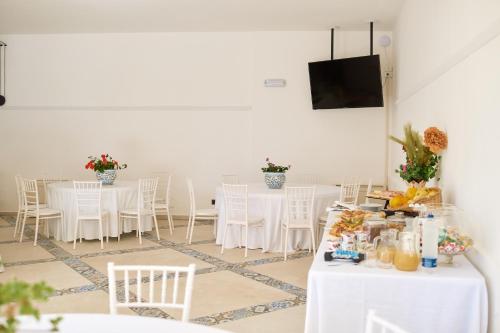 a room with white tables and chairs and a television at Villa Vittoria Hotel in Alcamo