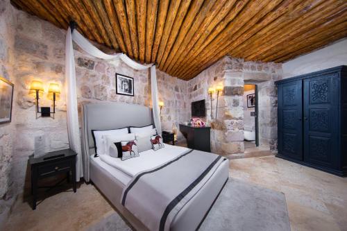 a bedroom with a large bed and a stone wall at Vigor Cappadocia - Special Class in Uchisar