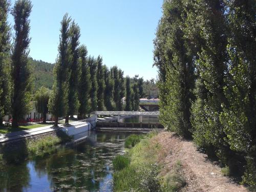 a river with trees and a bridge in the background at Casa O Arco Alojamento Local in Marvão
