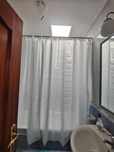 a bathroom with a shower curtain and a sink at Apartamento corrales in Chipiona