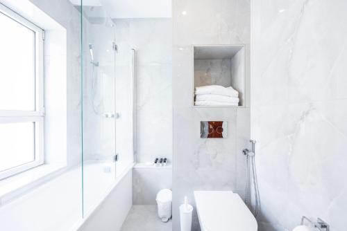 a white bathroom with a shower and a toilet at CARLTON COURT - MAYFAIR in London