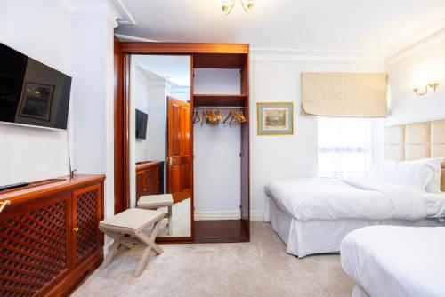 a hotel room with a bed and a tv and a bedroom at CARLTON COURT - MAYFAIR in London