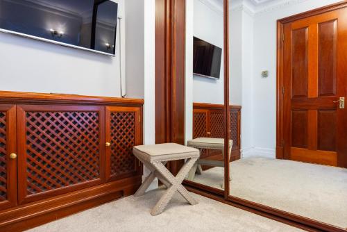 a stool in a room with a door and a television at CARLTON COURT - MAYFAIR in London