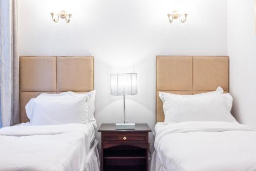 two beds with white sheets and a nightstand between them at CARLTON COURT - MAYFAIR in London