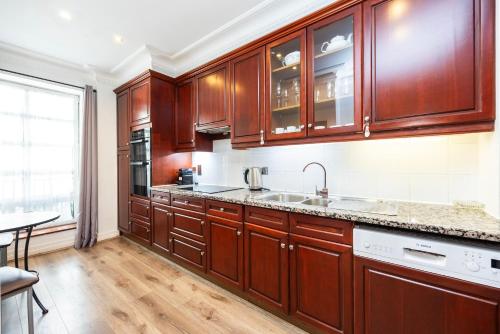 a kitchen with wooden cabinets and a sink at CARLTON COURT - MAYFAIR in London