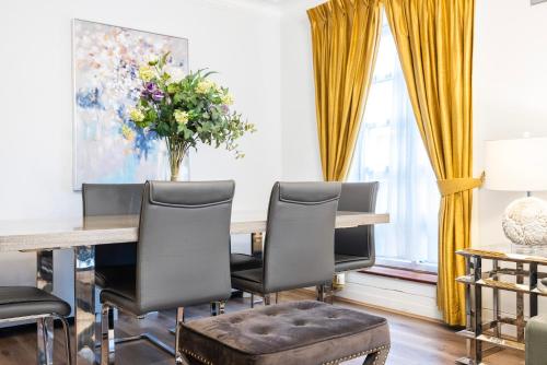a dining room with a table and chairs and a vase of flowers at CARLTON COURT - MAYFAIR in London