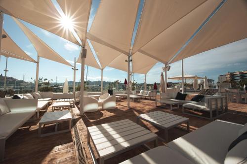 a rooftop patio with white chairs and umbrellas at Ibiza Corso Hotel & Spa in Ibiza Town
