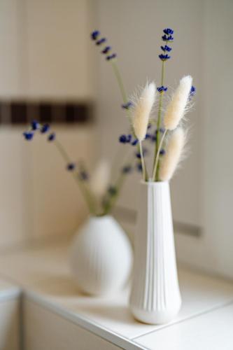 two white vases with feathers and blue flowers on a counter at Sonnenschein Hotel & Apartments in Heilbad Heiligenstadt