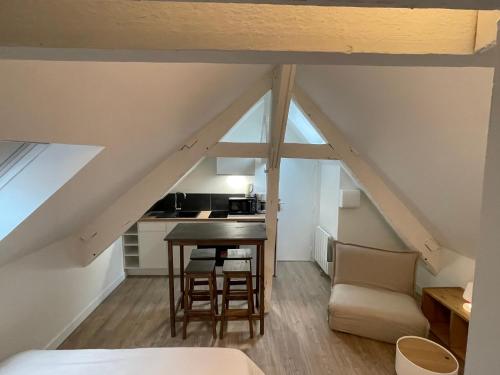 Cette chambre mansardée comprend une table et des chaises. dans l'établissement Ker Latitude 3 vieux Dinan, à Dinan