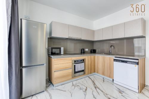 a kitchen with a stainless steel refrigerator and wooden cabinets at The St Pauls Bay Escape Suites by 360 Estates in St Paul's Bay