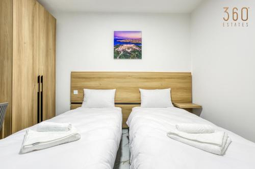 two beds in a room with white sheets at The St Pauls Bay Escape Suites by 360 Estates in St Paul's Bay
