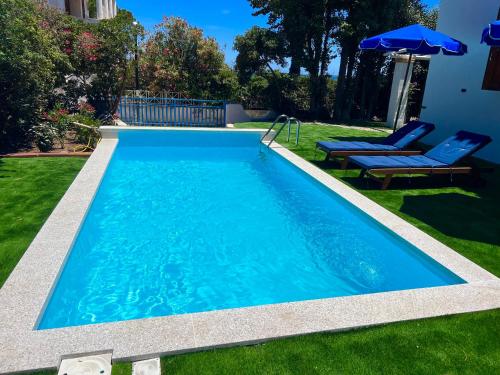 a swimming pool in a yard with two chairs and an umbrella at Casale fronte mare - villa with swimming pool in front of the beach in Porto Columbu - Perdʼe Sali