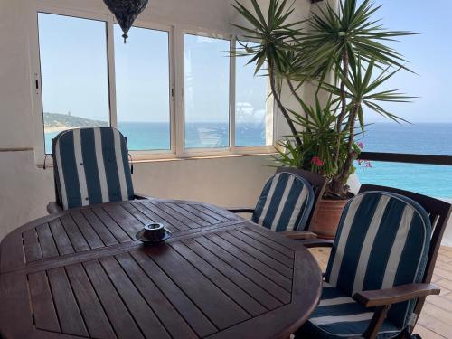 a wooden table and two chairs with a view of the ocean at Chalet El Encanto in Zahara de los Atunes